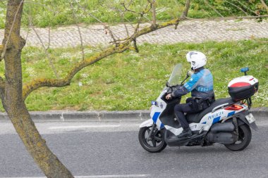 Devriye görevi sırasında motosiklet süren bir polis memuru, şehir merkezinde güvenlik ve düzeni sağlıyor.