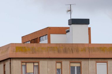 Eski televizyon anteni, çatıda yosun ve kepenklerle duruyor ve modası geçmiş bir teknolojiyi çağrıştırıyor.