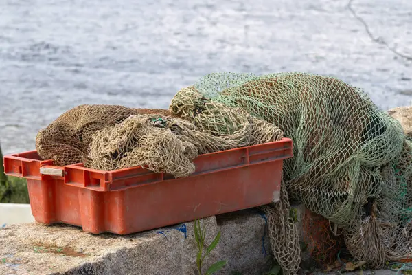 Balık ağları suyun yakınındaki turuncu plastik bir sandıkta kuruyor.