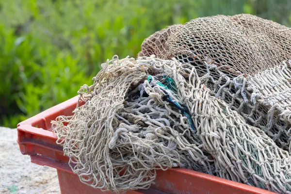 Kullanılmış balık ağları kırmızı plastik bir sandıkta kuruyor. Balıkçılar için bir gün dinlenme zamanı.