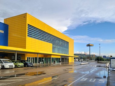 Loule, Portekiz 'deki IKea mağazasının modern mimari tasarımı, sarı cephe ve park alanı içerir.