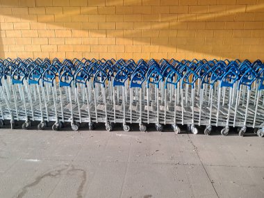 Mavi saplı pek çok metal alışveriş arabası Portekiz 'deki bir ikea mağazasında müşterileri bekleyen sarı tuğlalı bir duvarın önünde durmaktadır.