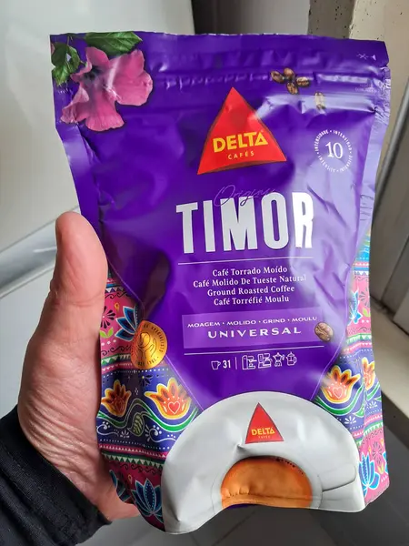 Elinde mor bir paket delta kafe timor kavrulmuş kahve, markasını ve kökenini vurguluyor.