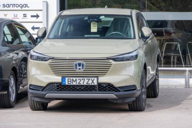 Resmi bir Honda Santogal bayiliğinin önüne park edilmiş yeni bir Honda HR V hibrid arabanın ön görüntüsü.