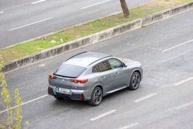 Kentsel çevrede asfalt yolda giden modern gri bmw ix1 elektrikli araba