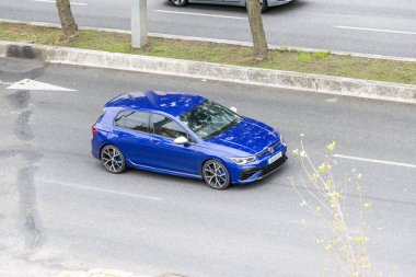 Modern mavi Volkswagen golf sahasında asfalt yolda araba sürmek.