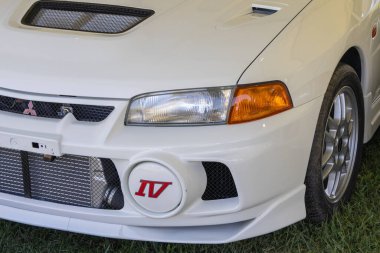 Beyaz Mitsubishi Lancer IV 'ün ön tampon, far ve IV rozetini kapatın.
