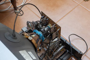 Parçalanmış klasik televizyon seti tamir ediliyor, karmaşık iç bileşenleri ve elektronik devreleri ortaya çıkarıyor