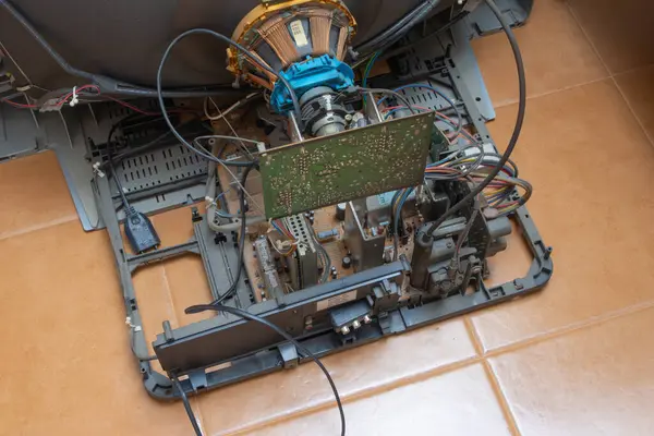 Parçalanmış bir crt televizyonun iç görüntüsü karmaşık elektronik bileşenlerini açığa çıkarıyor, yerde yatıyor.