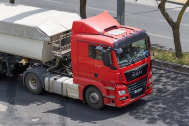 Kırmızı adam TGX kamyonu yolda mal taşıyor, hava manzaralı.