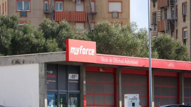 Myforce auto center building featuring prominent red signage, garage doors, and portuguese language inscriptions, suggesting automotive services