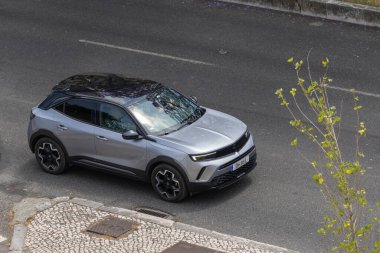 Gökyüzünden görünen asfalt yolda siyah çatılı şık gümüş opel mokka.