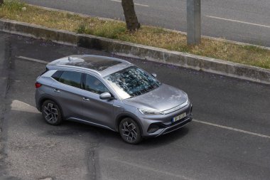 Modern gri elektrikli araba asfalt yolda gidiyor, hava manzaralı.