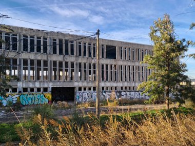 Kırık camları ve grafitileri olan terk edilmiş bir binanın dış cephesi, şehir çürümesini ve ihmalkarlığı simgeliyor.