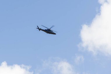 Lizbon 'un Humberto Delgado Havaalanı üzerinde kısmen bulutlu bir havada uçan modern helikopter.