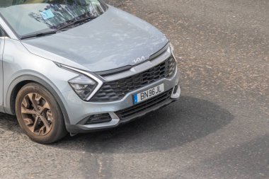 Modern gümüş kia spor arazi aracı asfalt yolda gidiyor.