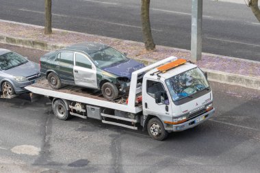 Çekici, bir trafik kazasından sonra hasarlı bir arabayı otoyolda taşıyor.