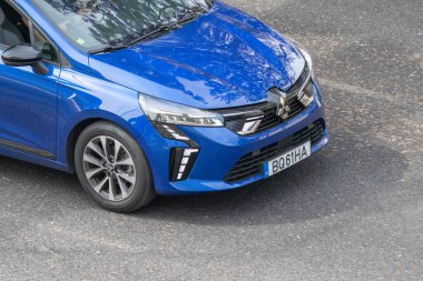 Yeni mavi renault klibi asfalt yolda sürüyor