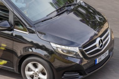 Modern siyah Mercedes Benz v sınıfı minivan güneşli bir günde sürüyor.