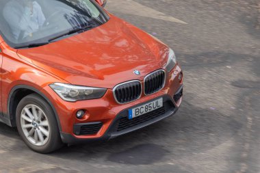 Turuncu bmw x1 asfalt yolda hızlı gidiyor
