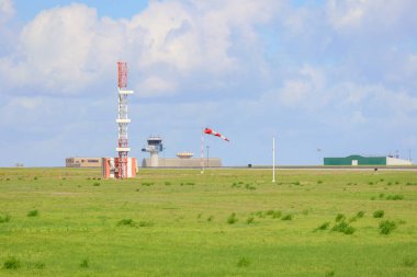 Windsock, Portekiz 'deki Lizbon havaalanında rüzgar yönünü gösteriyor. Kontrol kulesi ve arka planda anten var.