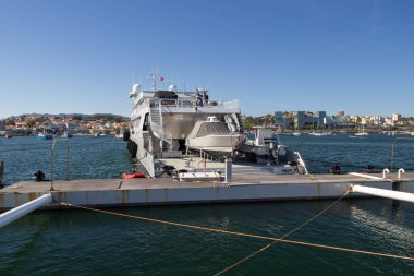 Büyük lüks yat dalgaları rıhtımda demirlemiş, gemi seyahatine hazır, kıç platformunda hassas tekneleri var.