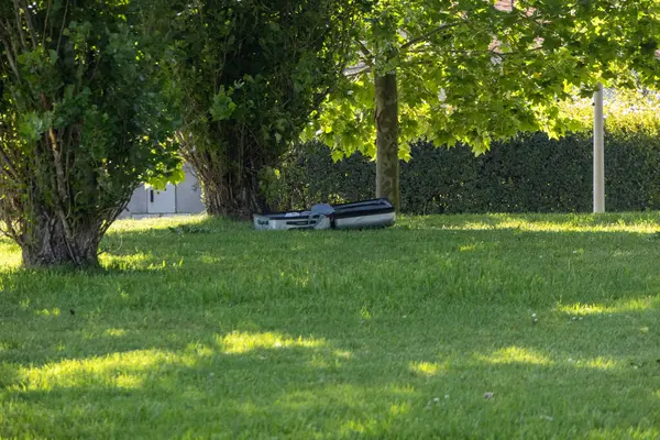 Otomatik robot çim biçme makinesi ağaçların gölgesinde dinleniyor.