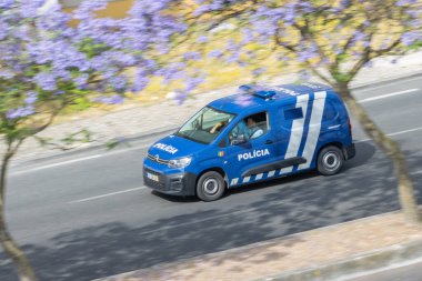 Portekiz polis devriyesi yola çıkmış. Çiçek açan jakaranda ağaçlarının altında.