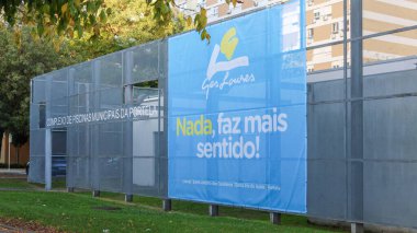 Üzerinde ges loures logosu ve sloganı olmayan büyük mavi bir pankart, faz mais sentido. Portela belediyesinin havuz kompleksinin dışındaki bir çitte görüntülendi