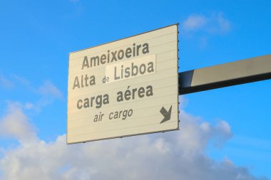 Lizbon 'un Humberto Delgado havaalanındaki hava kargo terminalinin yönünü gösteren tabela. Güzel mavi gökyüzü ve beyaz bulutlar.