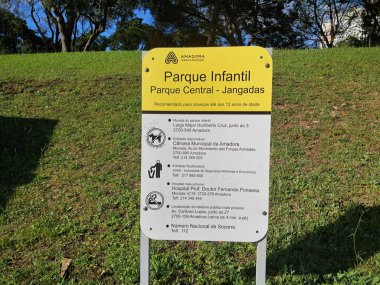 Bilgilendirici tabela, Amadora Central Park 'taki parktaki çocuk parkında kurallar, iletişim detayları ve yakınlardaki konforları gösterir.