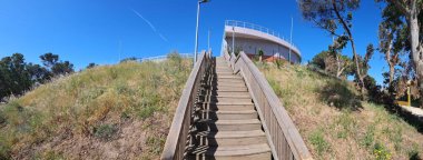 Yükselen ahşap merdiven, Portekiz, Oeiras 'ta açık mavi bir gökyüzünün altındaki alto de Santa Catarina rezervuarına çıkıyor.