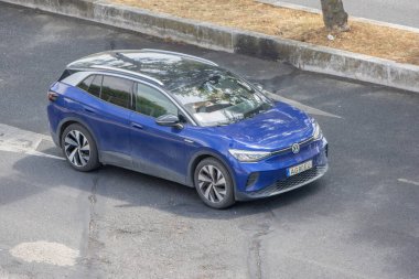 Şehir yolunda giden mavi elektrikli bir arabanın havadan görüntüsü.