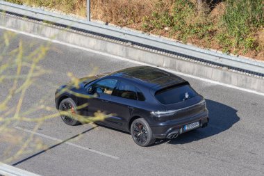 Koyu gri Porsche Maccan otoyolda sürüyor.