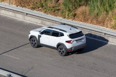 Modern beyaz dacia koşucusu otoyolda güneşli bir günde araba sürüyor.