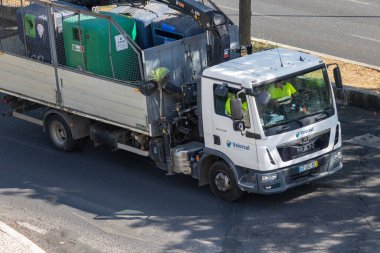 Çöp kamyonu, çöp konteynırlarını gündüz vakti şehir sokaklarına taşıyor ve temel atık yönetimi hizmetlerini sunuyor.