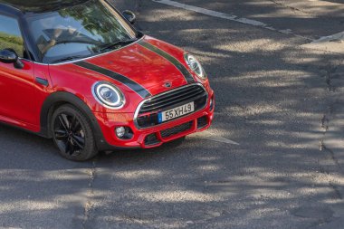 Şehir sokaklarında gezinen kırmızı bir mini Cooper 'ın hava görüntüsü şehir hareketliliğini ve ulaşımı vurguluyor.