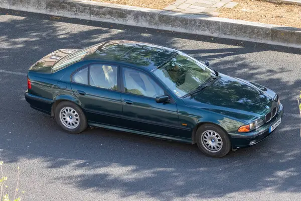 Güneşli bir günde asfalt yolda giden yeşil BMW Sedan.