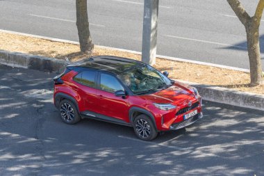 Modern kırmızı toyota yaris yolun kenarına park edilmiş, gösterişli tasarımı ve kentsel pratikliği sergileniyor.