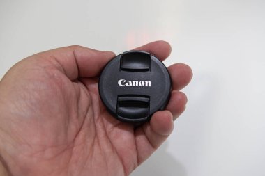 Canon mercek kapağı tutan fotoğrafçı, kamera lenslerini çizik ve tozdan koruyor.
