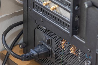 Bir masaüstü bilgisayarına bağlı güç kablosu olan bir güç kaynağı ünitesini kapat, bağlantıyı ve güç anahtarını vurgula