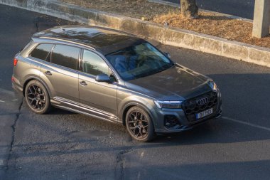 Modern gri Audi Q8 lüks SUV asfalt yolda kaldırımın yanında park etmiş.