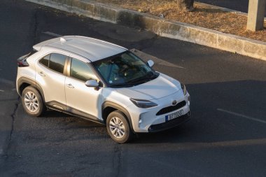 Günbatımında asfalt yolda giden modern beyaz çapraz araba.