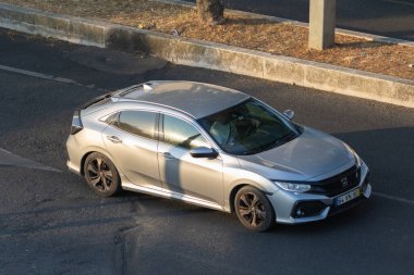 Gümüş rengi Honda Civic Hatchback asfalt yolda altın saat ışığının altında