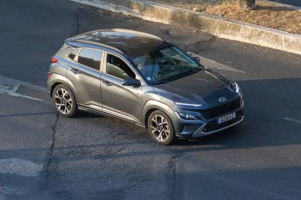 Modern Hyundai Kona arabası asfalt yolda gidiyor.