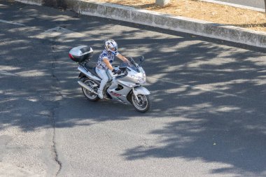 Kask takan motosikletçi asfalt yolda motosiklet turu yapıyor.