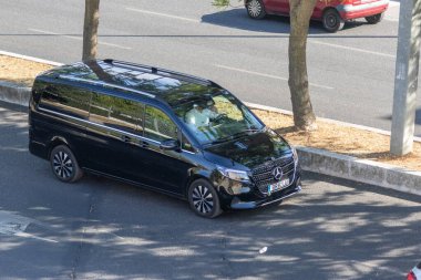 Şehir caddesinde siyah Mercedes Benz Eqv marka bir minibüsün hava görüntüsü, şehir hareketliliğini ve ulaşımı gösteriyor.