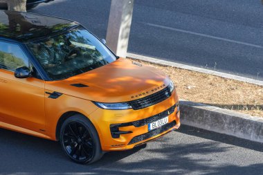 Turuncu Range Rover Velar yolda gidiyor.