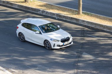 Kentsel çevrede asfalt yolda giden modern beyaz bmw 1 serisi araba