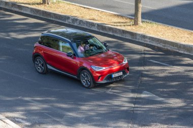 Şehirde asfalt yolda giden kırmızı akıllı bir araba.